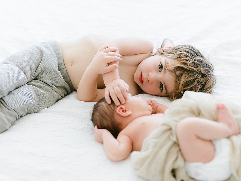 Big brother snuggling new brother during newborn pictures