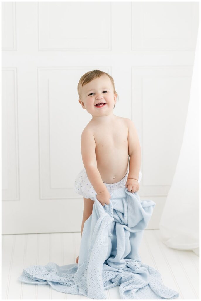 One year old baby holding a blue blanket in a Savannah Newborn Photographer Studio